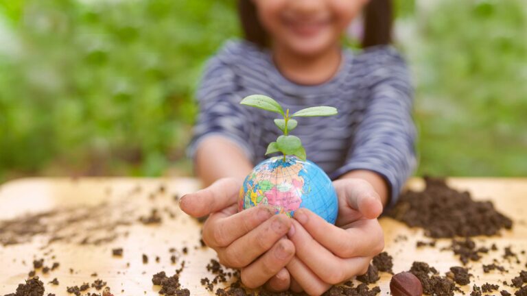 environmental issues. Photo of young person holding a globe with and a plant.